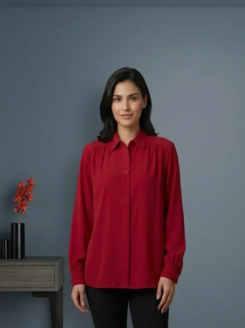 Woman wearing a red shirt standing against a gray background