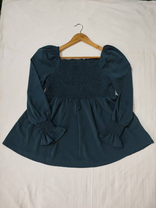 Teal blouse with puff sleeves on a hanger against a white background