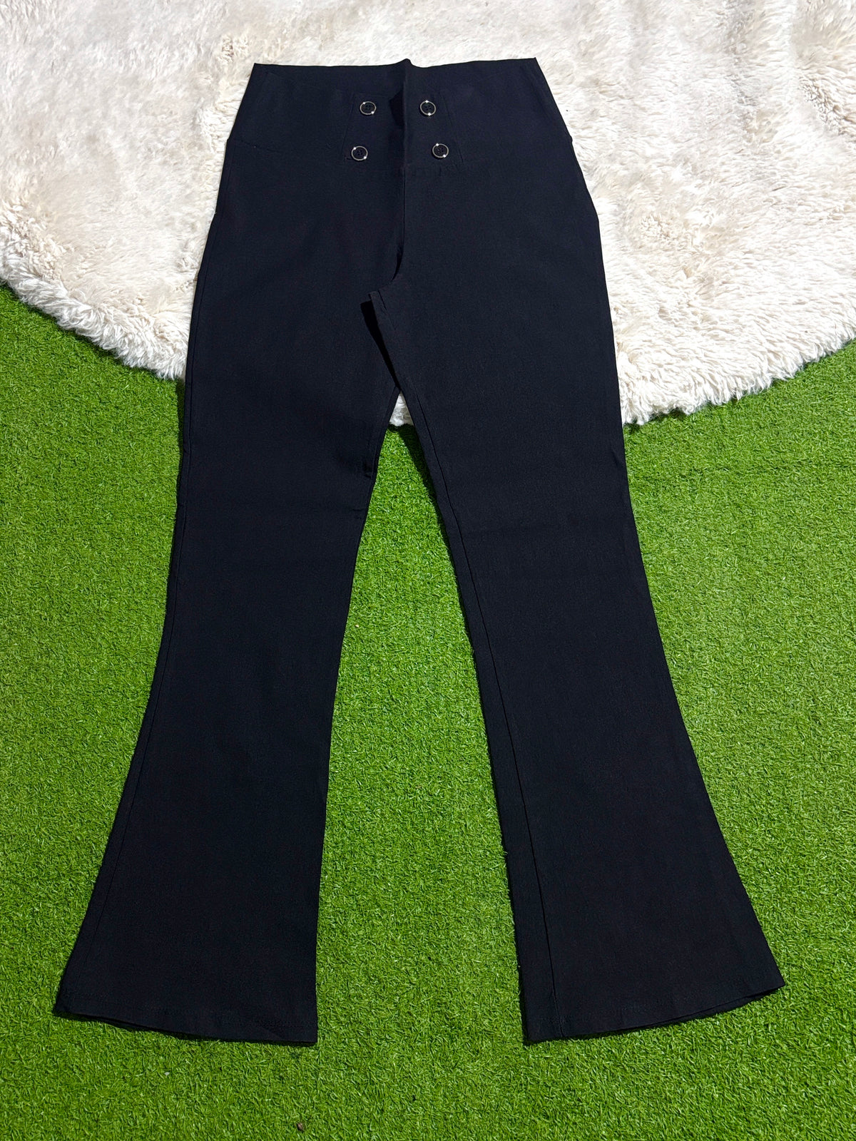 Black flared trousers with four-button front detail laid flat