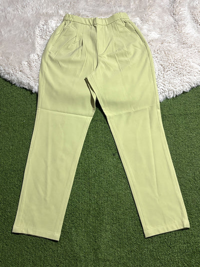 Pistachio green pleated tapered pants laid flat