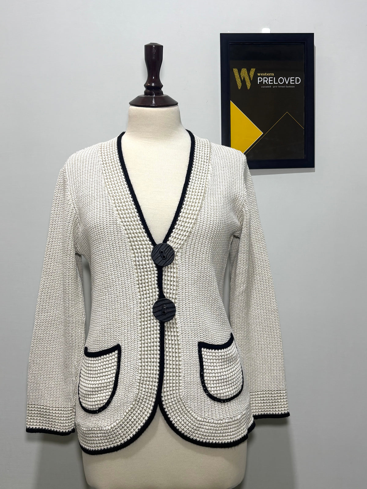 Cream knit button-front cardigan with contrast black trim and patch pockets