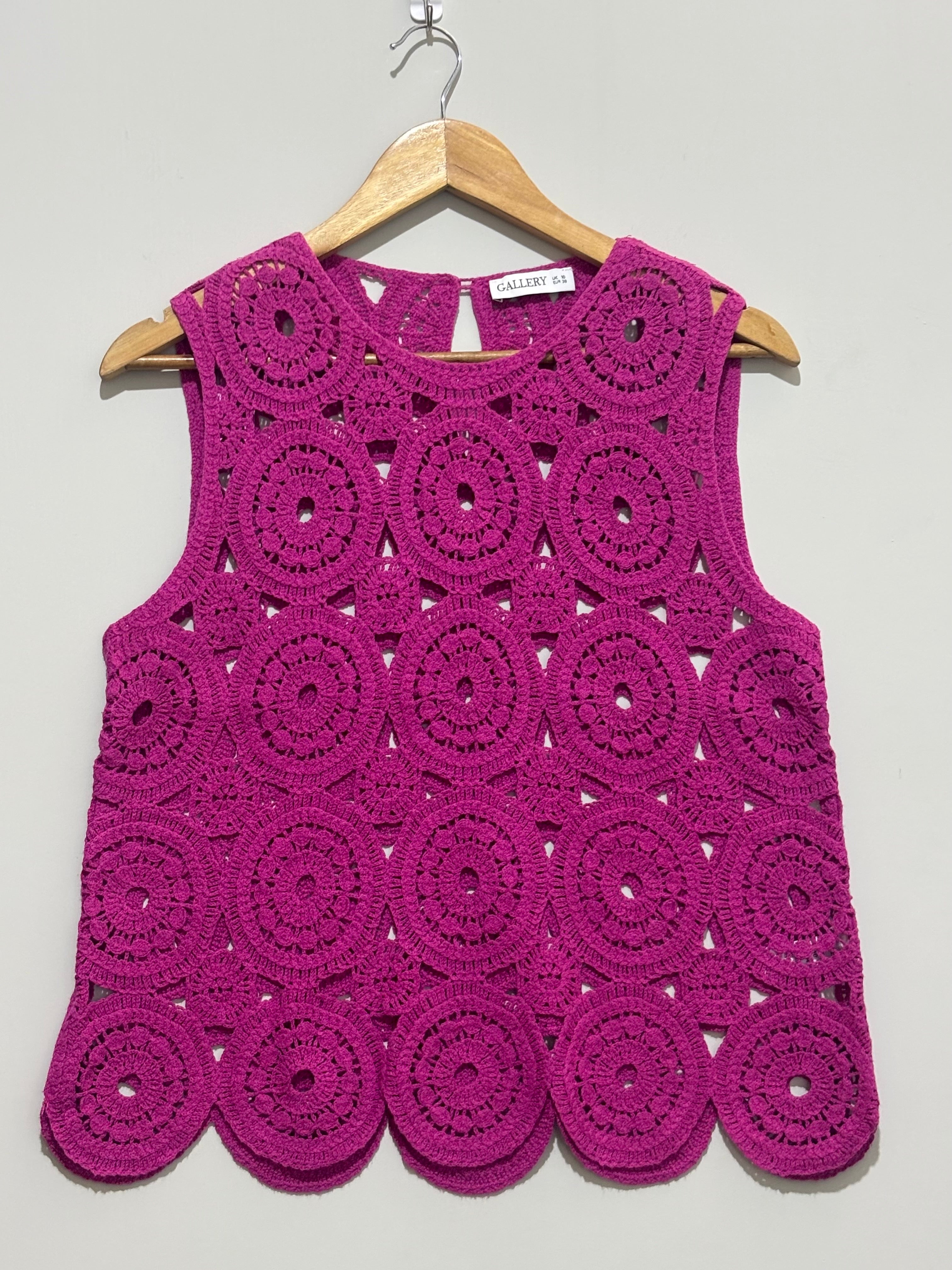 Magenta sleeveless top with circular openwork motifs and scalloped hem