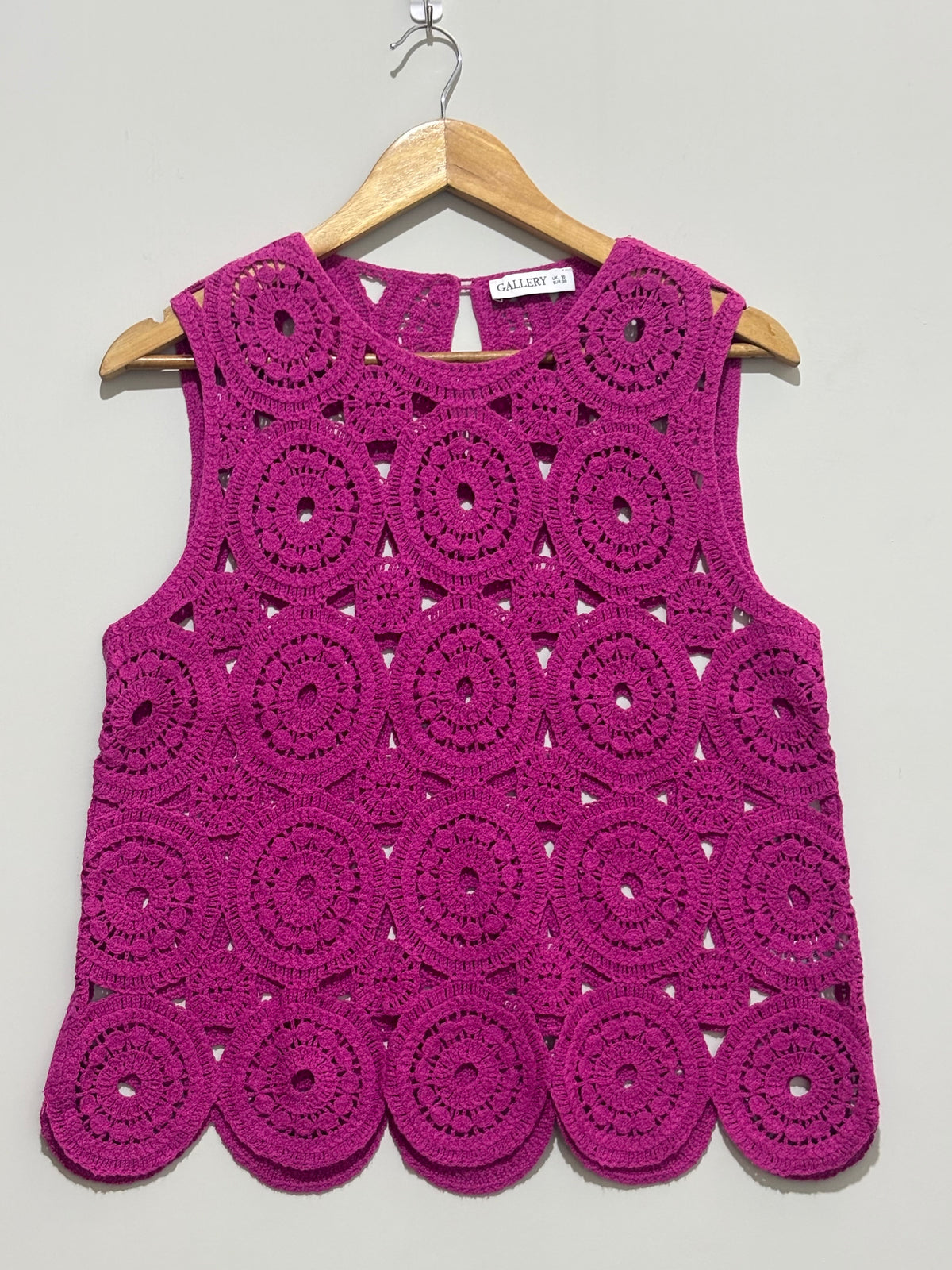 Magenta sleeveless top with circular openwork motifs and scalloped hem