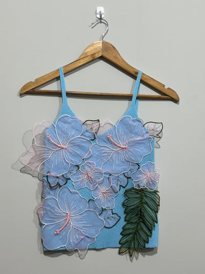 Light blue strappy top with layered floral appliqués and green leaf accents