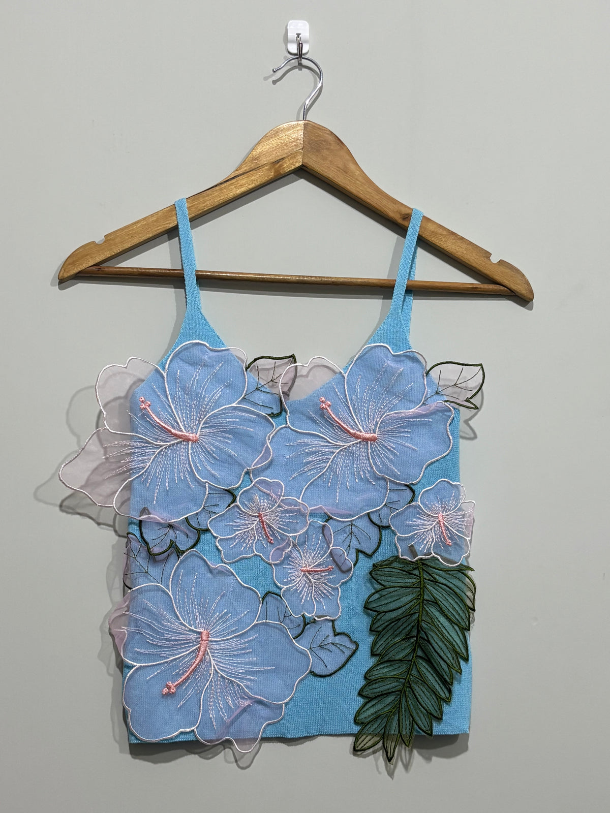 Light blue strappy top with layered floral appliqués and green leaf accents