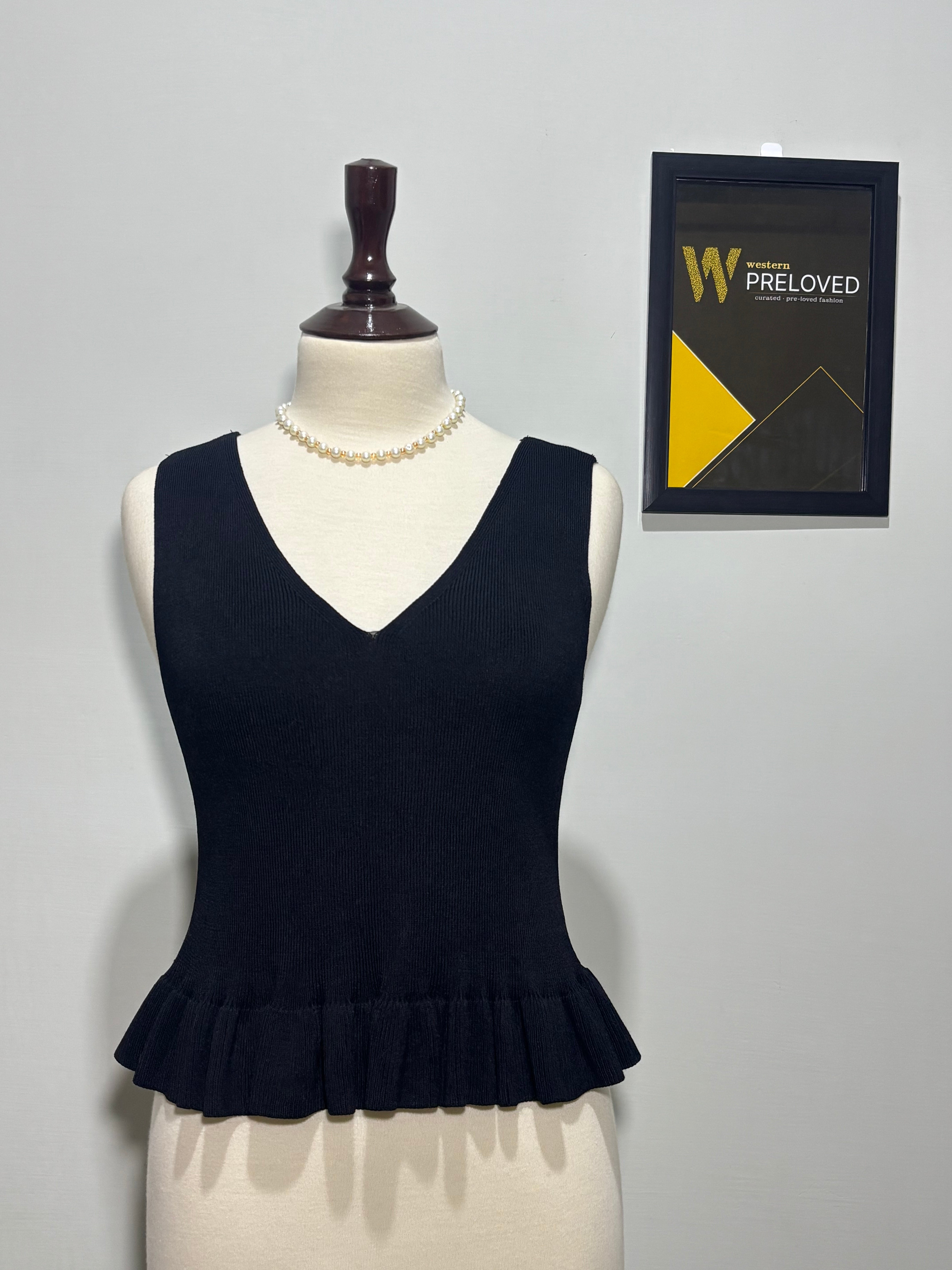 Black sleeveless V-neck top with flared ruffle hem