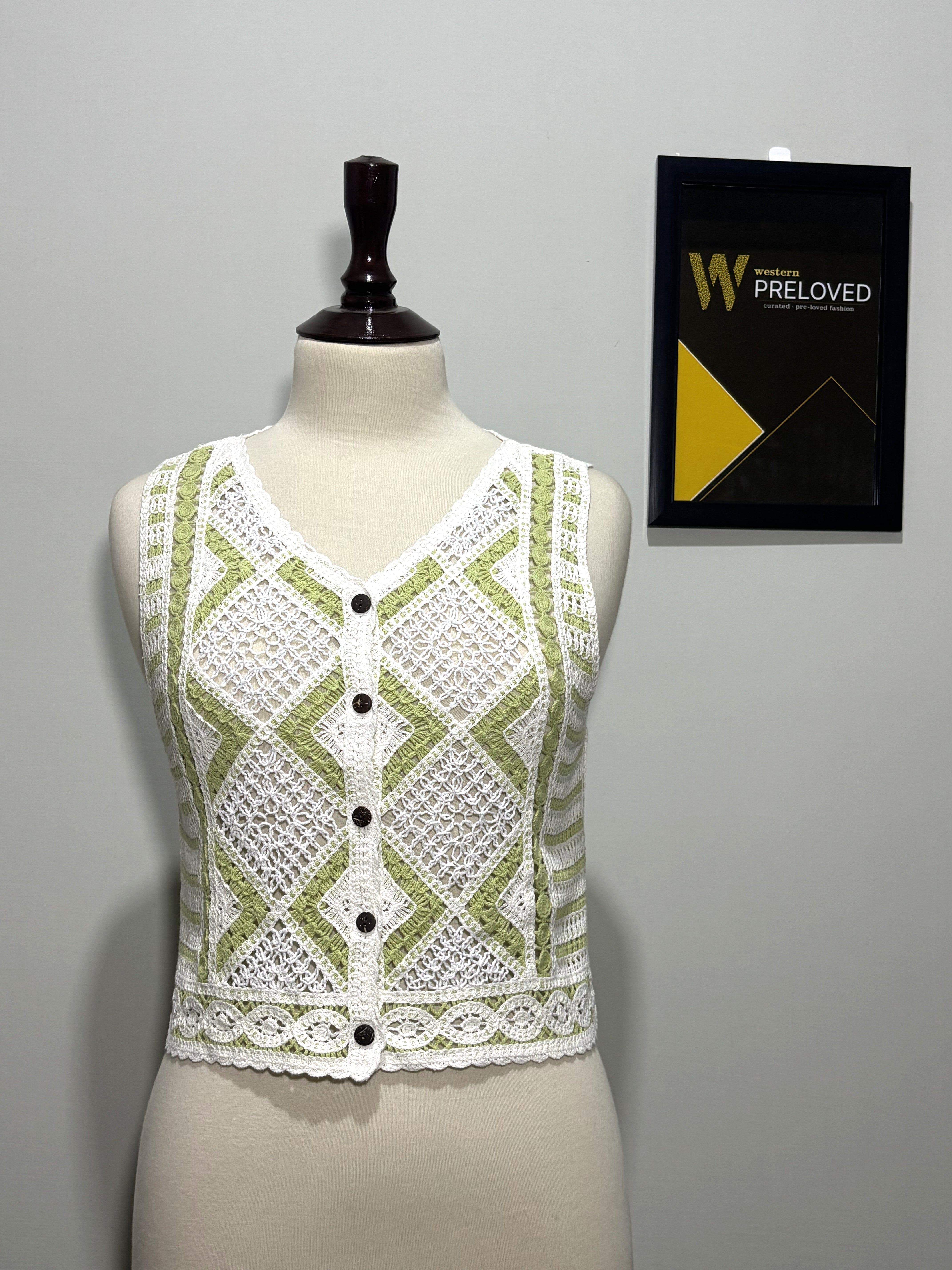 Green and white openwork button-front sleeveless crop top on mannequin