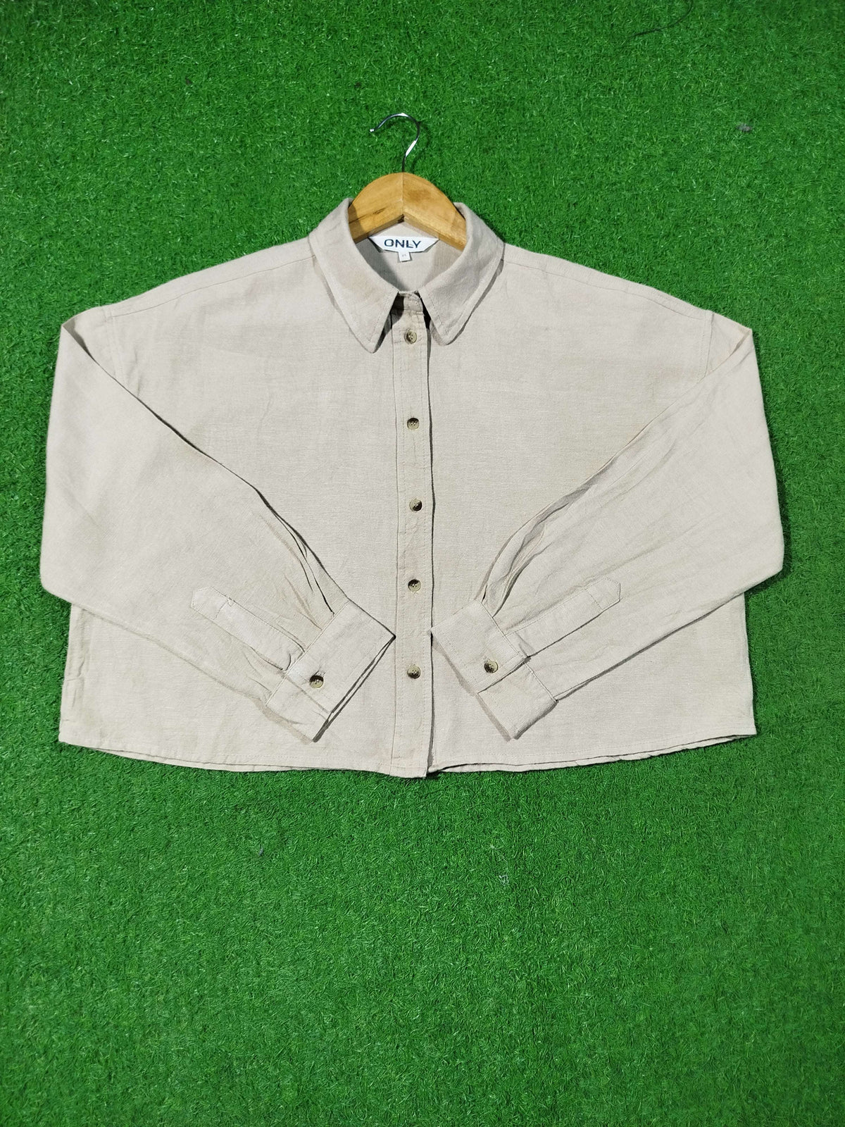 Beige shirt on a hanger against a green background