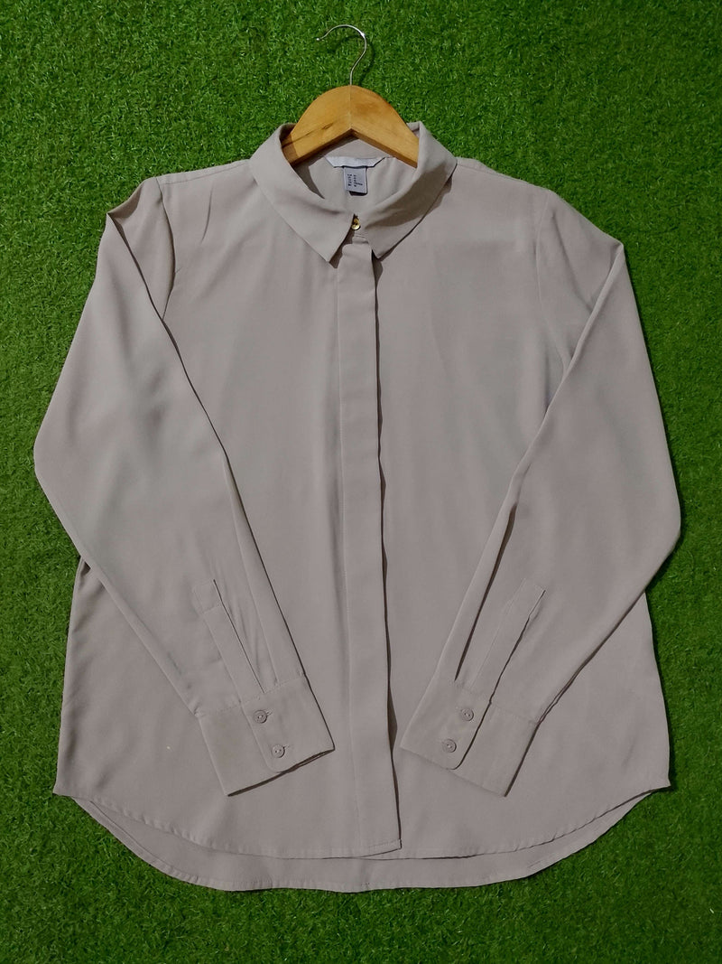 Light gray shirt on a hanger against a green textured background