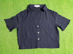 Black shirt with white buttons on a green textured surface