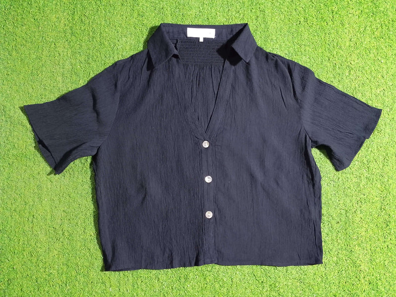Black shirt with white buttons on a green textured surface