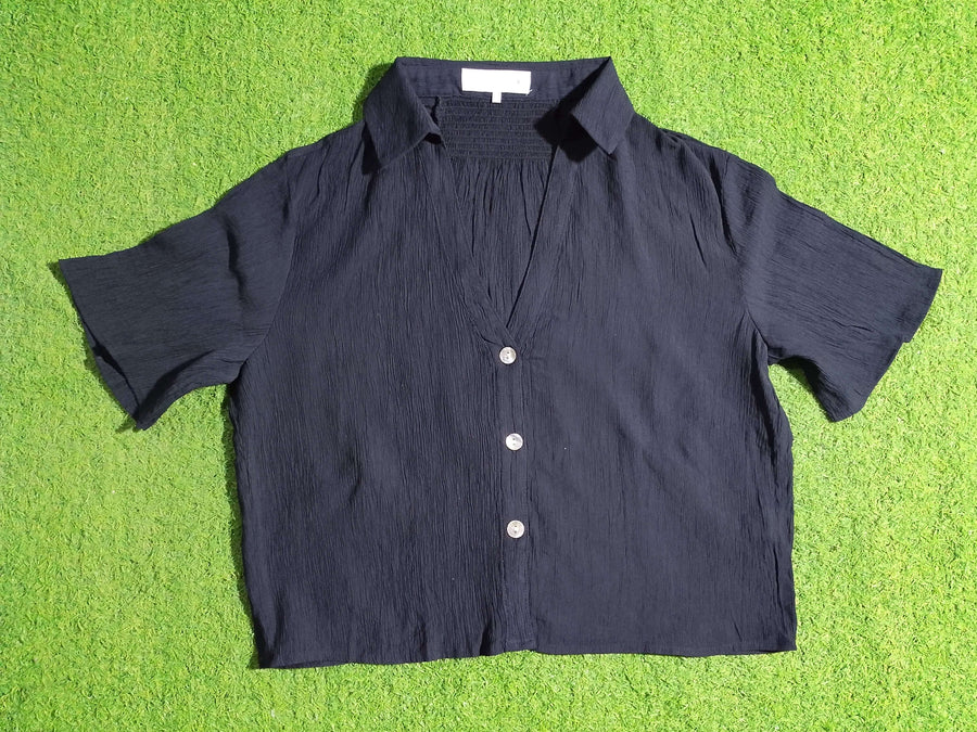 Black shirt with white buttons on a green textured surface