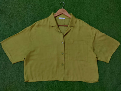 Green shirt on a hanger against a green background - alternate view