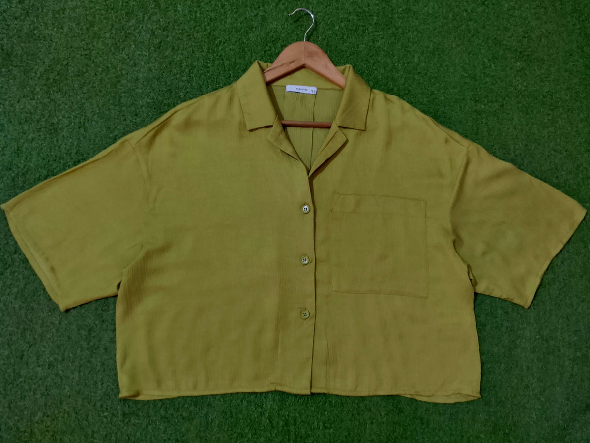 Green shirt on a hanger against a green background