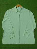 Light green shirt on a hanger against a green background