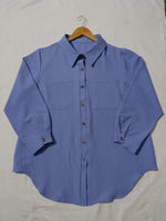 Blue shirt on a hanger against a plain background