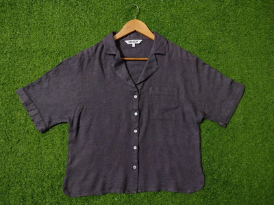 Dark gray short-sleeve shirt on a hanger against a green grass background - alternate view