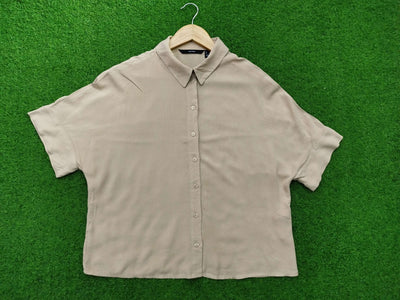 Beige short-sleeve shirt on a hanger against a green background - alternate view