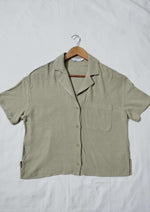 Green short-sleeve shirt on a hanger against a white background