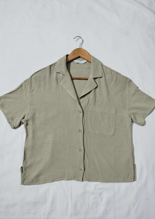 Green short-sleeve shirt on a hanger against a white background