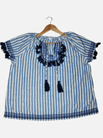 Blue and white striped blouse with tassels on a hanger against a white background