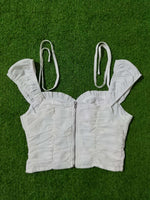 White ruffled top and shorts set on a green grass-like background
