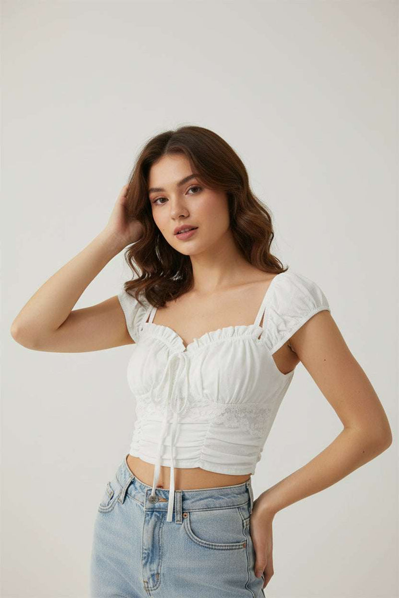 White lace top with straps on a green grass background