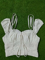 White lace top with straps on a green grass background
