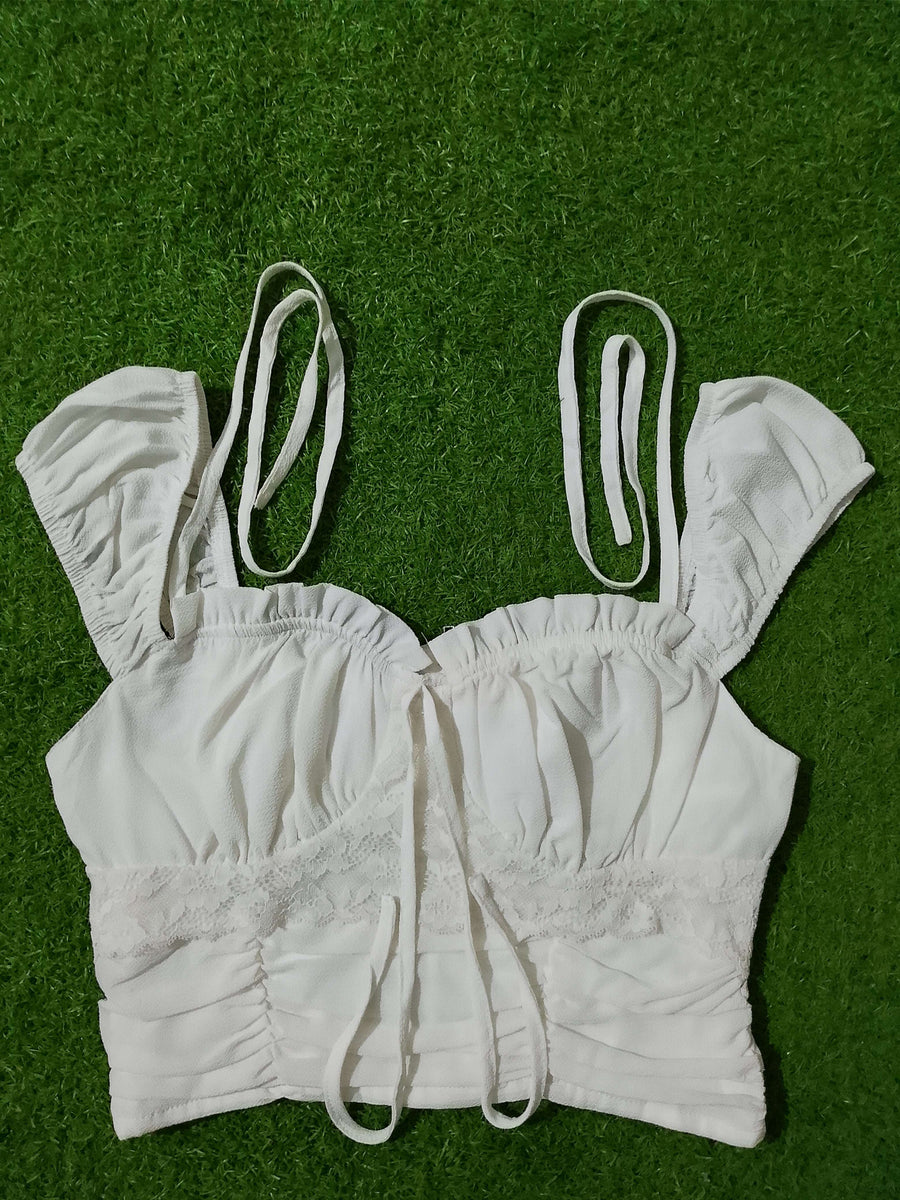 White lace top with straps on a green grass background - alternate view