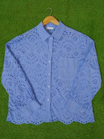 Blue lace shirt on a hanger against a green background