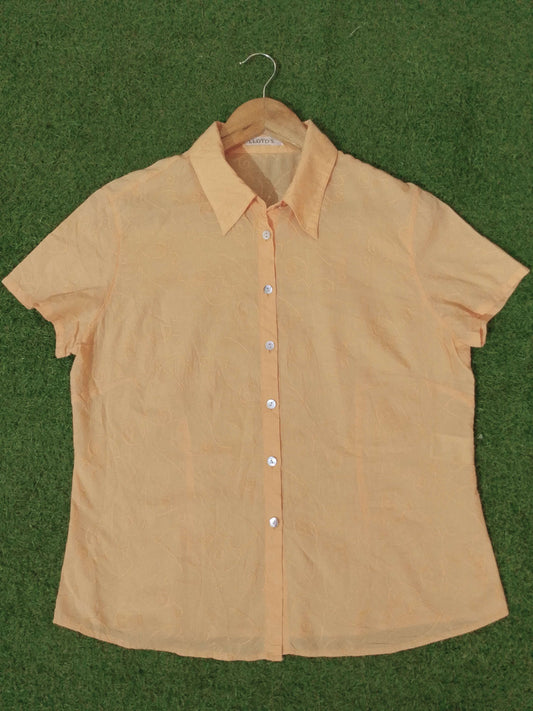 Beige shirt on a hanger against a green background