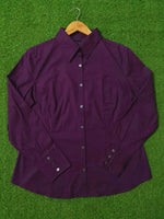 Purple shirt on a wooden hanger against a green grass background