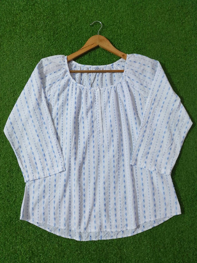 White blouse with blue patterns on a wooden hanger against a green background