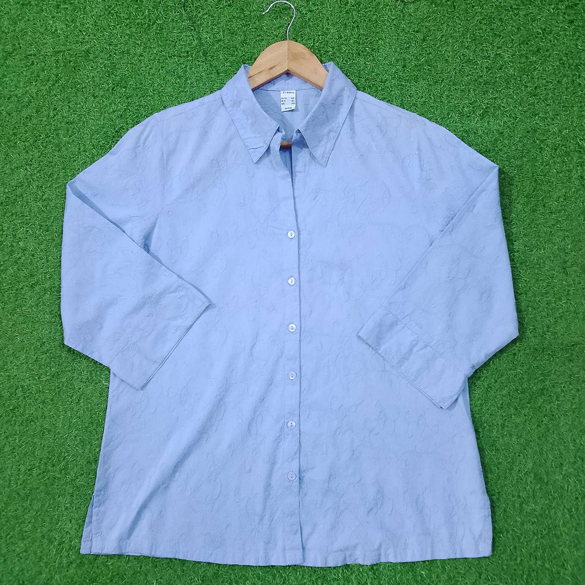 Blue button-up shirt on a green surface
