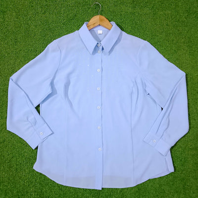 Light blue button-up shirt on a wooden hanger against a green grass background