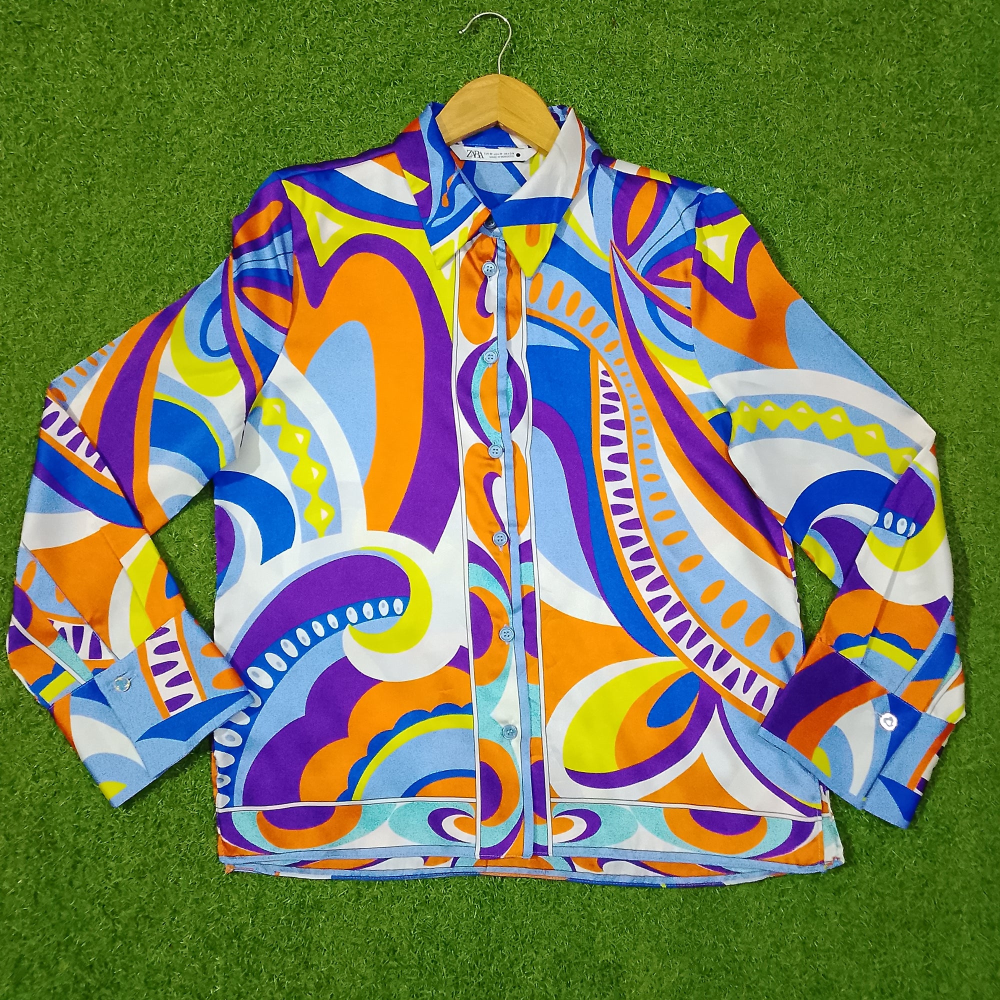 Colorful patterned jacket on a hanger against a green background