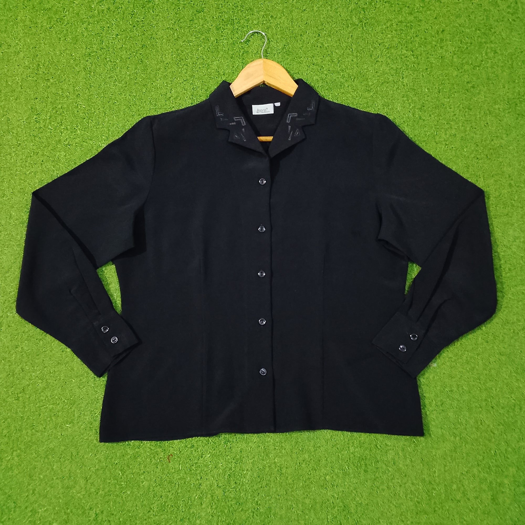 Black shirt on a hanger against a green grass-like background