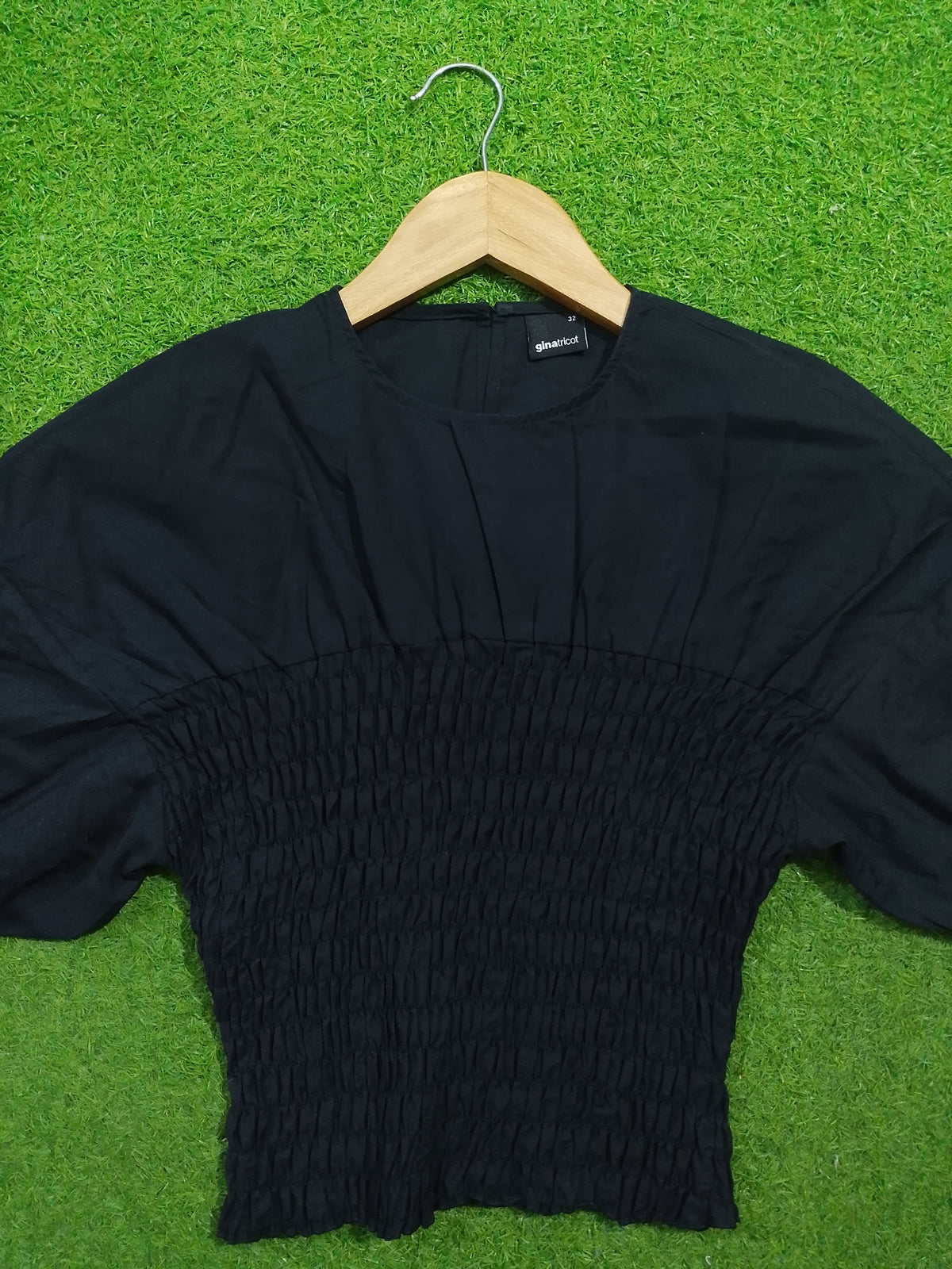 Black smocked drop shoulder flared sleeve crop top - front view on hanger