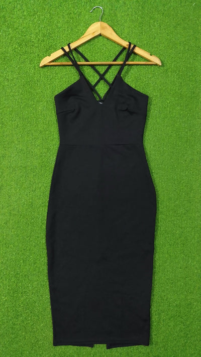 A black sleeveless bodycon dress with thin crisscross shoulder straps, hanging on a wooden hanger against a bright green textured background. - alternate view