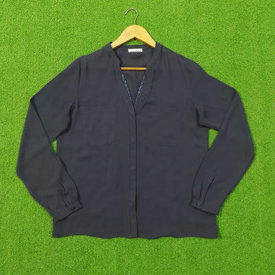 A dark charcoal gray long-sleeve button-up blouse with a split V-neckline, laid flat on a wooden hanger against a bright green artificial grass background.