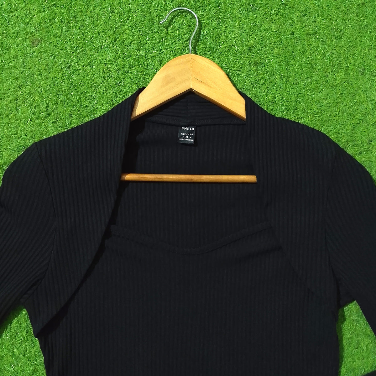 Shein label close-up on black ribbed knit shrug top