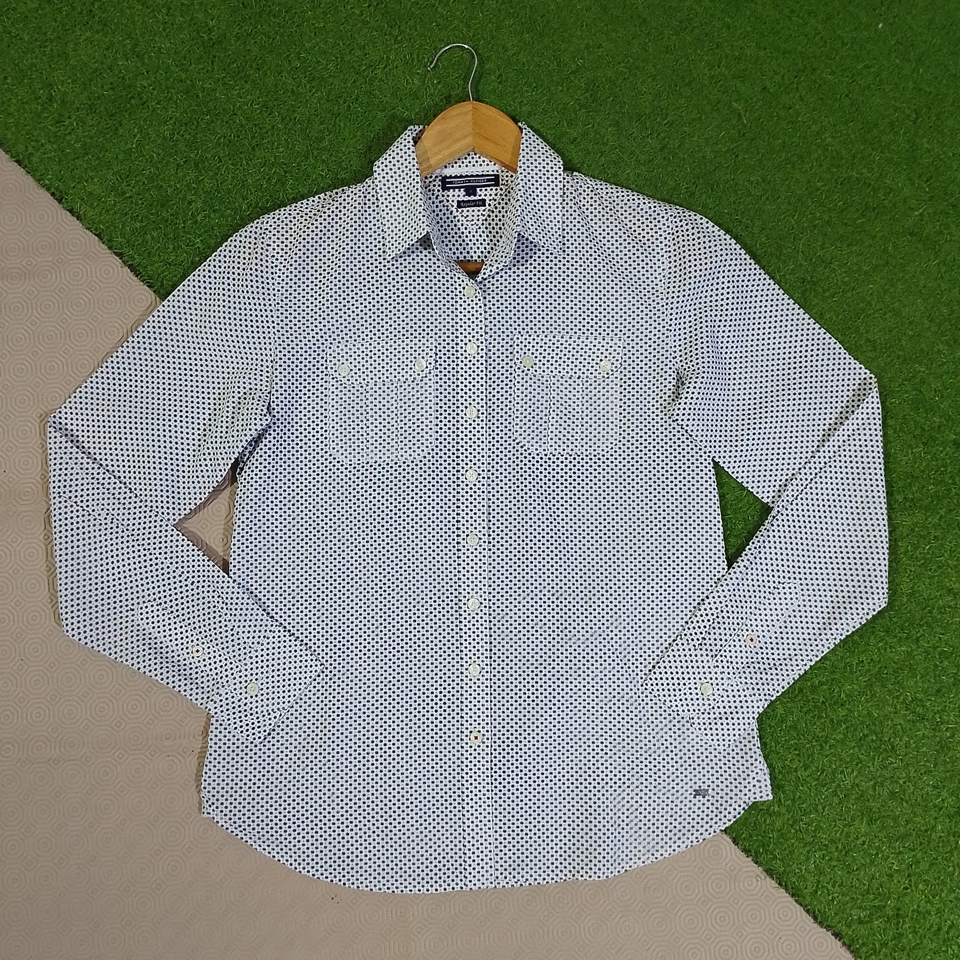 White shirt with black floral print, double chest pockets and buttoned cuffs on a wooden hanger