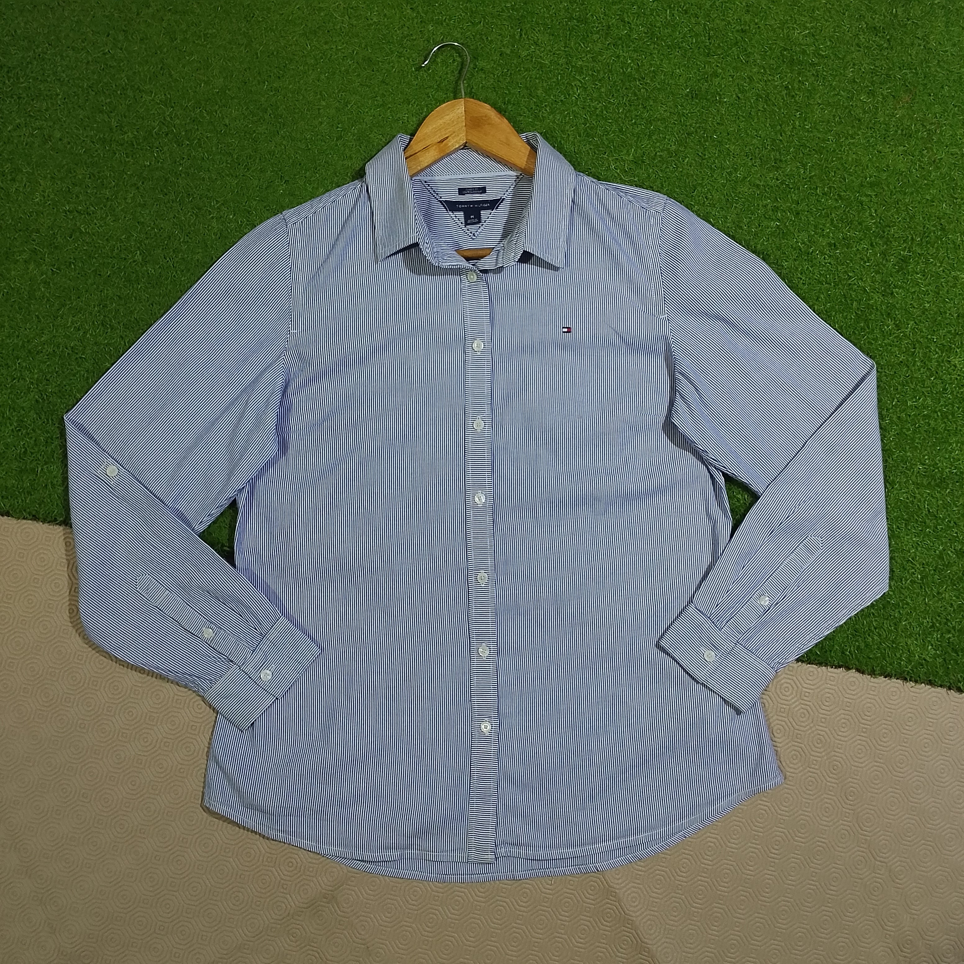 Blue and white striped collared button-down shirt with chest pocket on a wooden hanger