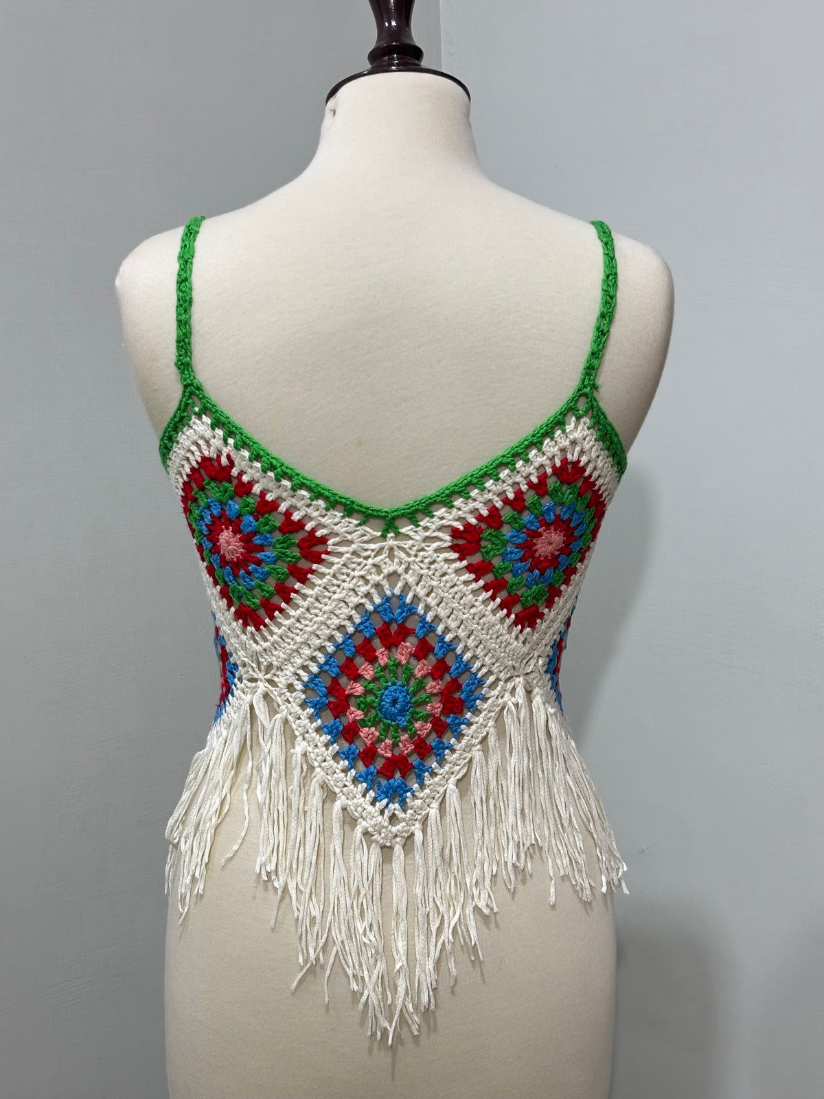 Back of cream and multicolor floral crochet top with long fringe