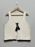 Cream and black textured sleeveless vest with tassel tie, buttons and scalloped hem