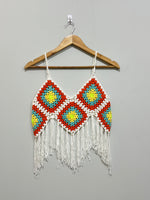 White and orange crochet crop top with yellow and turquoise motifs on hanger