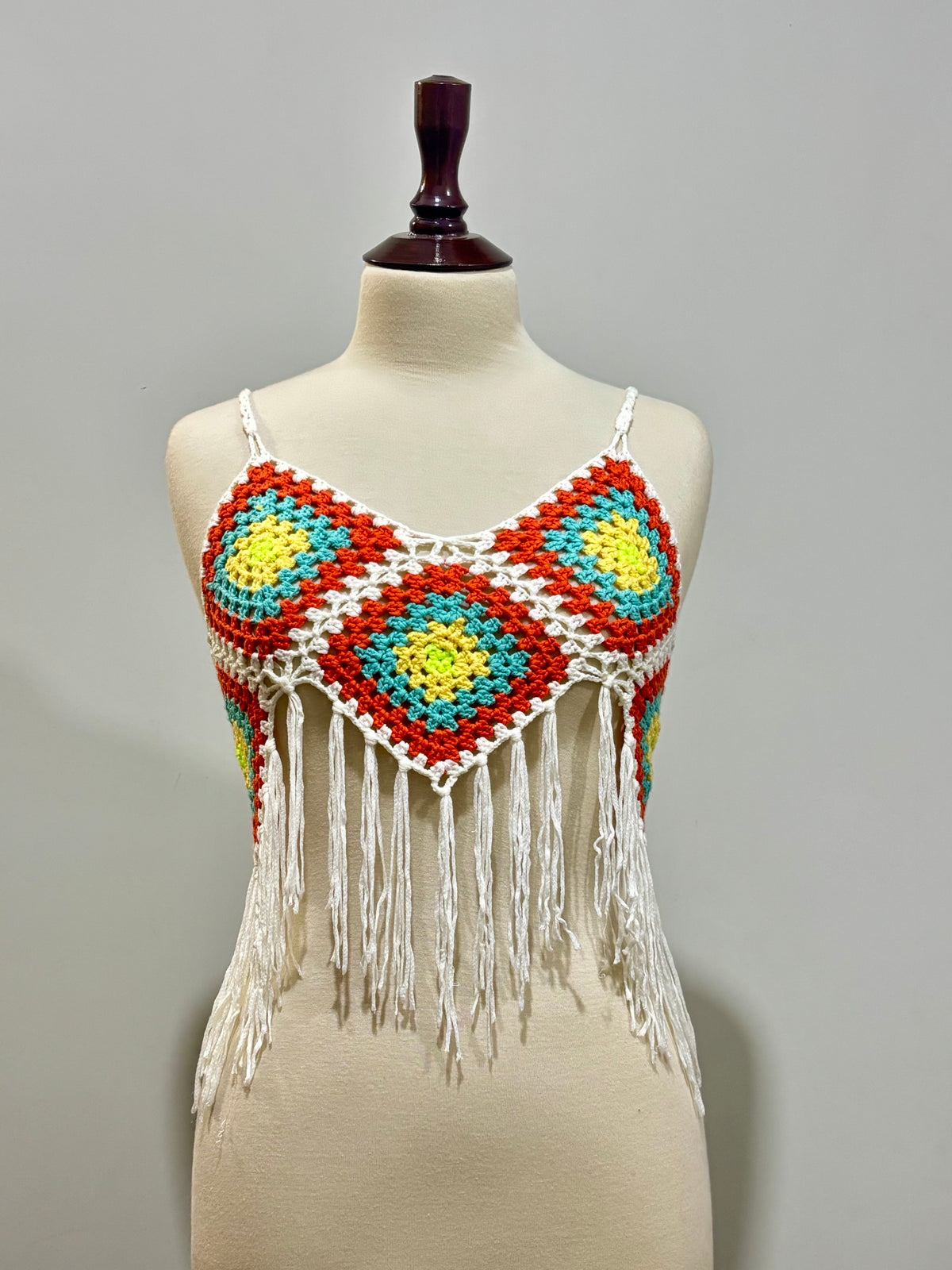 White and orange multicolor crochet fringe-hem crop top on mannequin