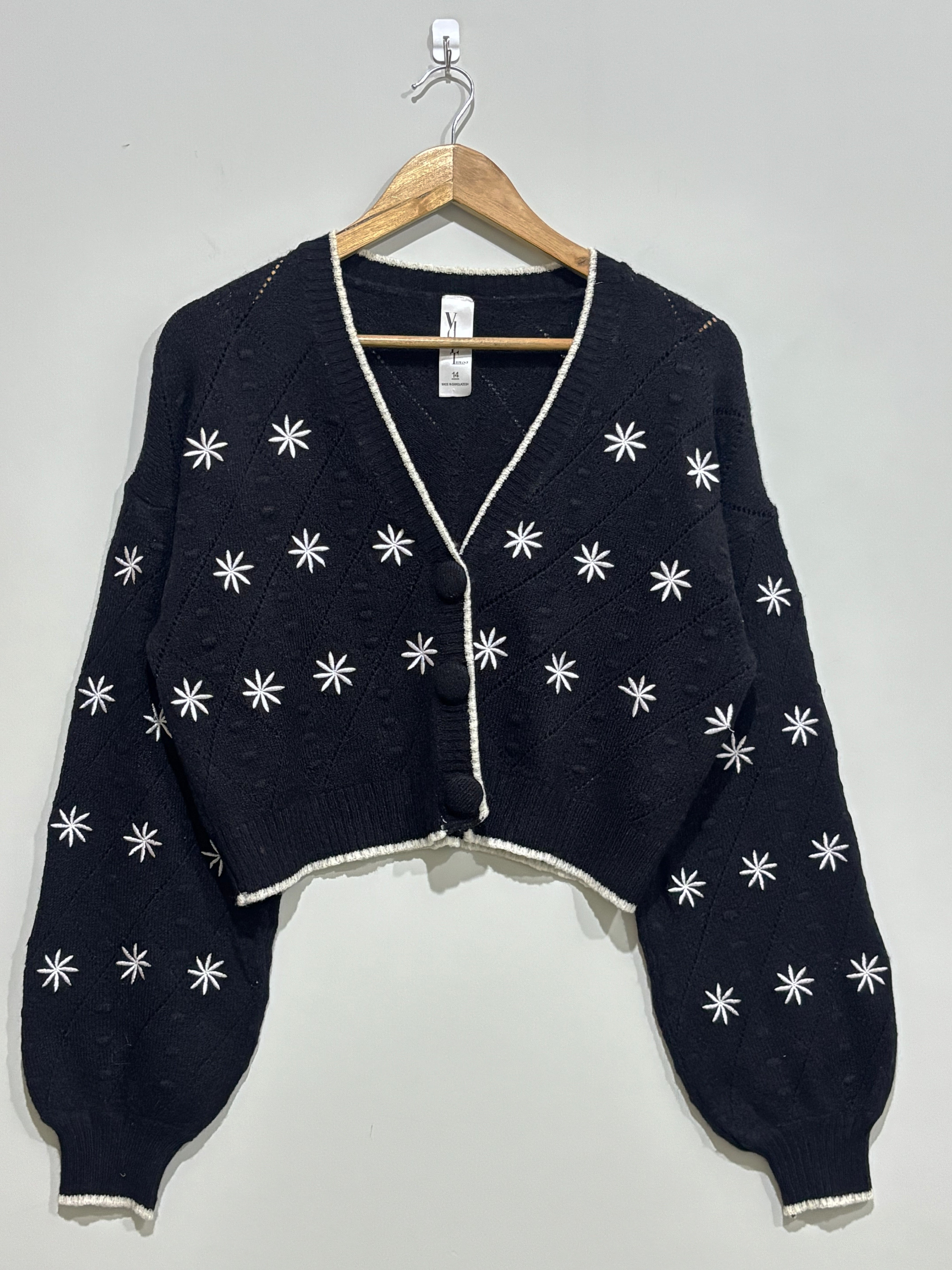 Black cropped V-neck cardigan with white starburst embroidery, light contrast edging, dropped shoulders and voluminous long sleeves.