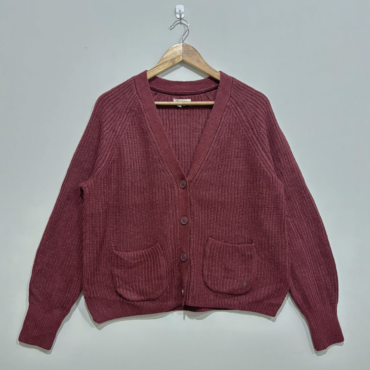 Burgundy textured V-neck cardigan with raglan sleeves, three front buttons, two patch pockets and ribbed cuffs and hem.