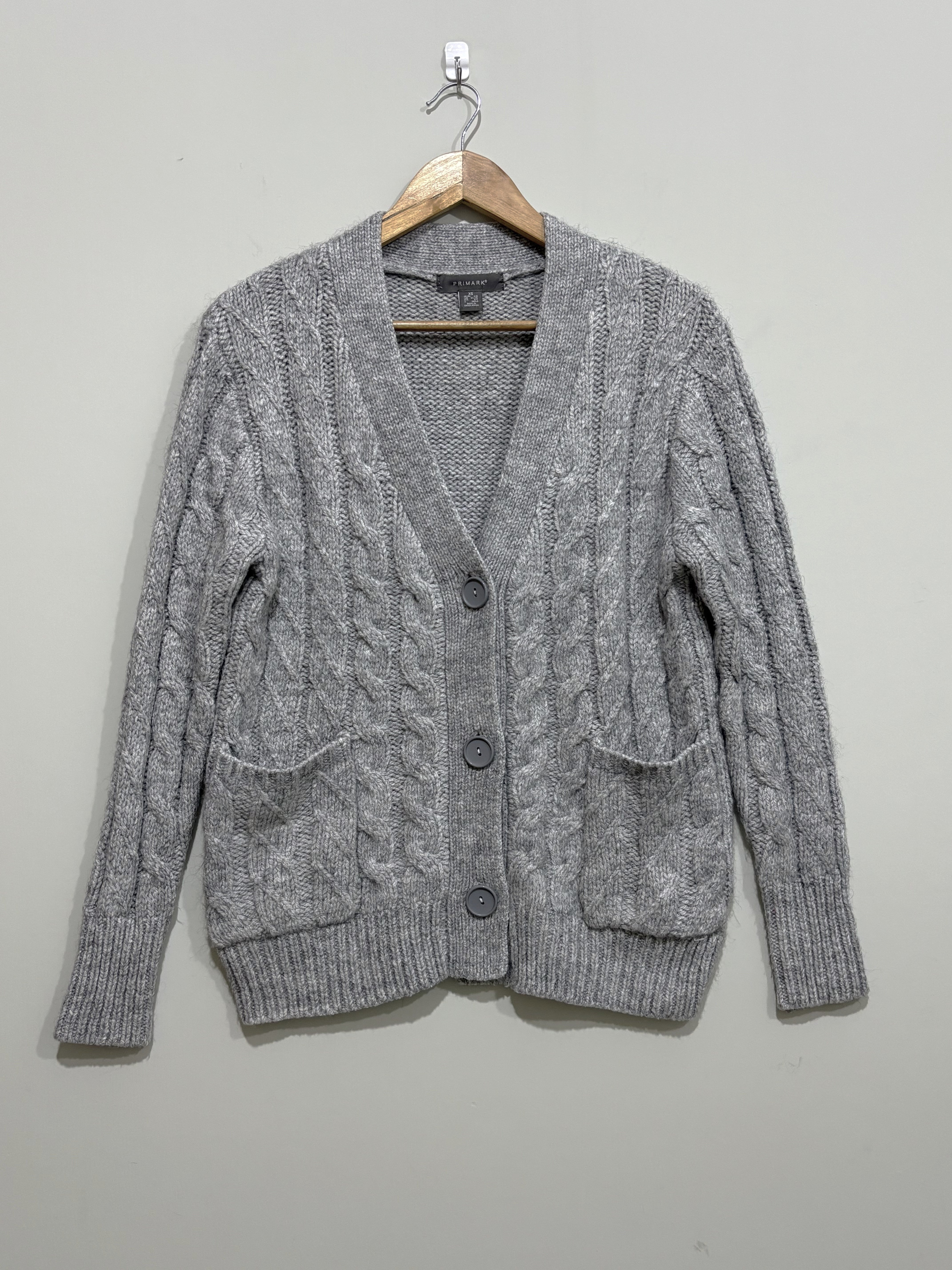Grey cable-knit V-neck cardigan with three front buttons, two patch pockets, long sleeves and ribbed cuffs and hem.